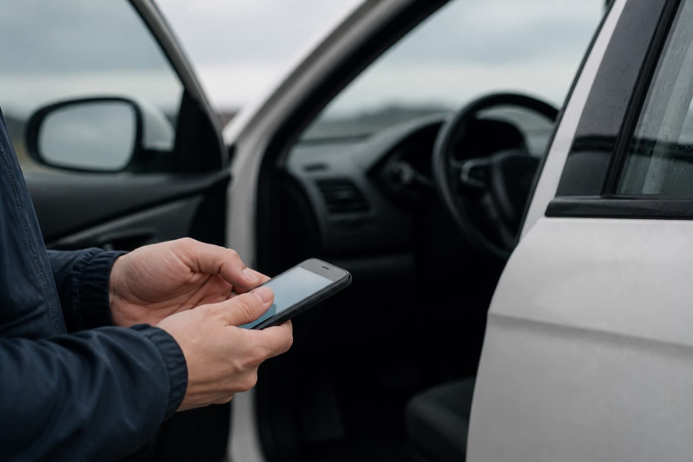 En köpare läser en Pssst-koll i mobilen framför en begagnad bil